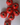 A collection of glossy red ceramic tomato candle holders and mini vases, perfect for dining decor.